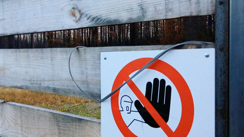 Imagen en primer plano de una tranquera cerrada con detalle de un cartel de prohibido el paso.