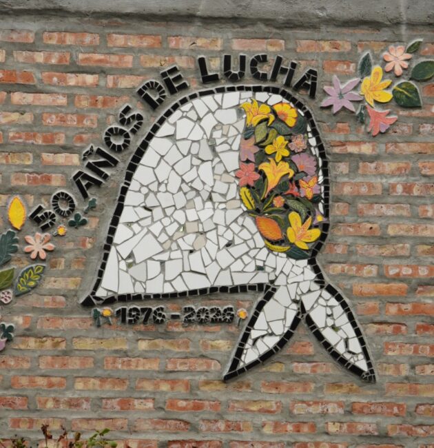 Mural en mosaico con un pañuelo planco característico de las madres y abuelas de Plaza de Mayo del que surgen flores de muchos colores. Sobre el pañuelo se lee la frase: 1976 - 2026 50 años de lucha.
