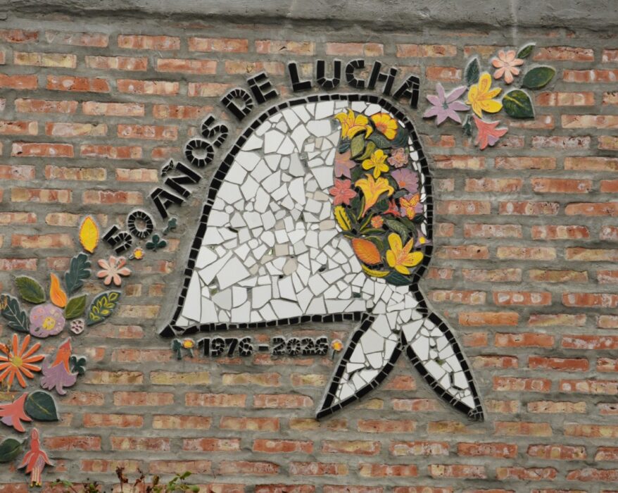 Mural en mosaico con un pañuelo planco característico de las madres y abuelas de Plaza de Mayo del que surgen flores de muchos colores. Sobre el pañuelo se lee la frase: 1976 - 2026 50 años de lucha.